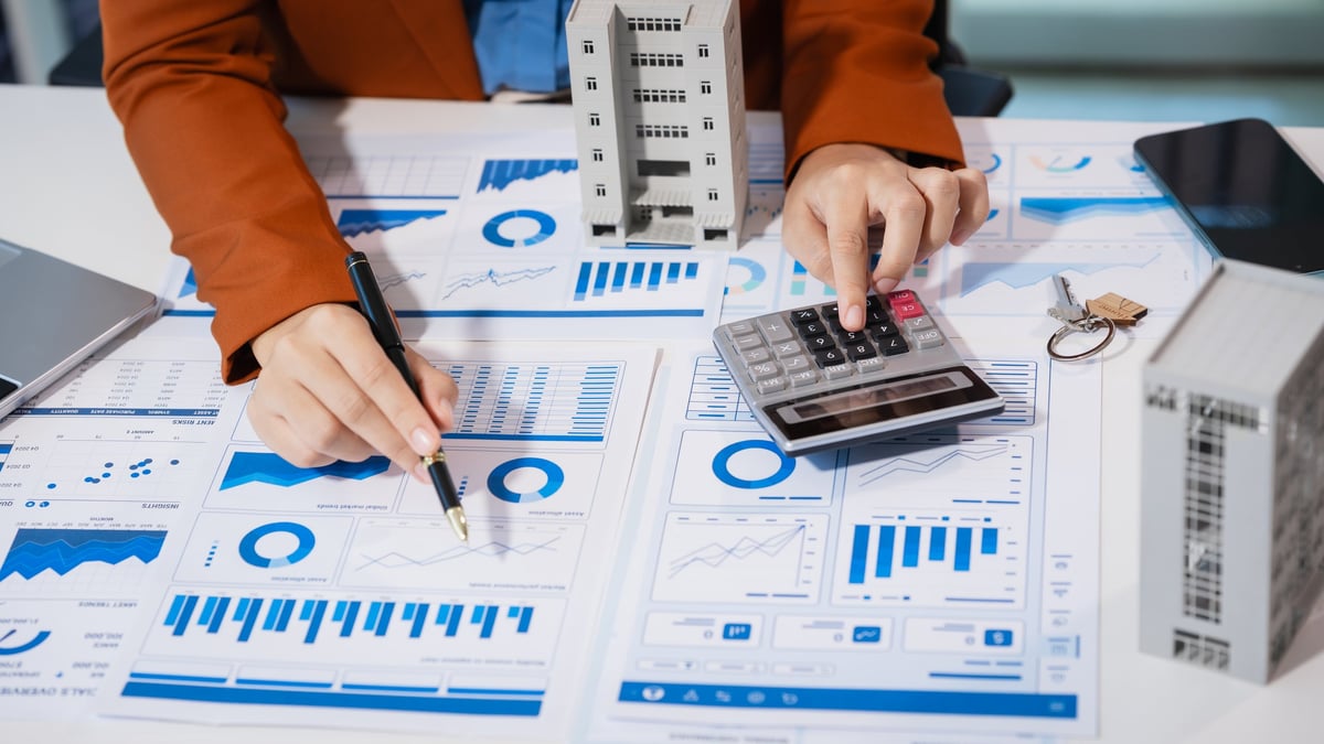 People reviewing financial charts with a calculator on a desk